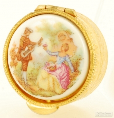 YBM & porcelain pill box, multi-colored image of a woman picking flowers and a man playing a guitar